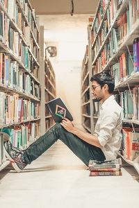 Young man reading on library floor