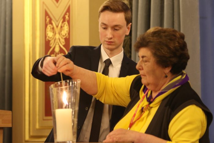 Young man and older woman lighting a candle