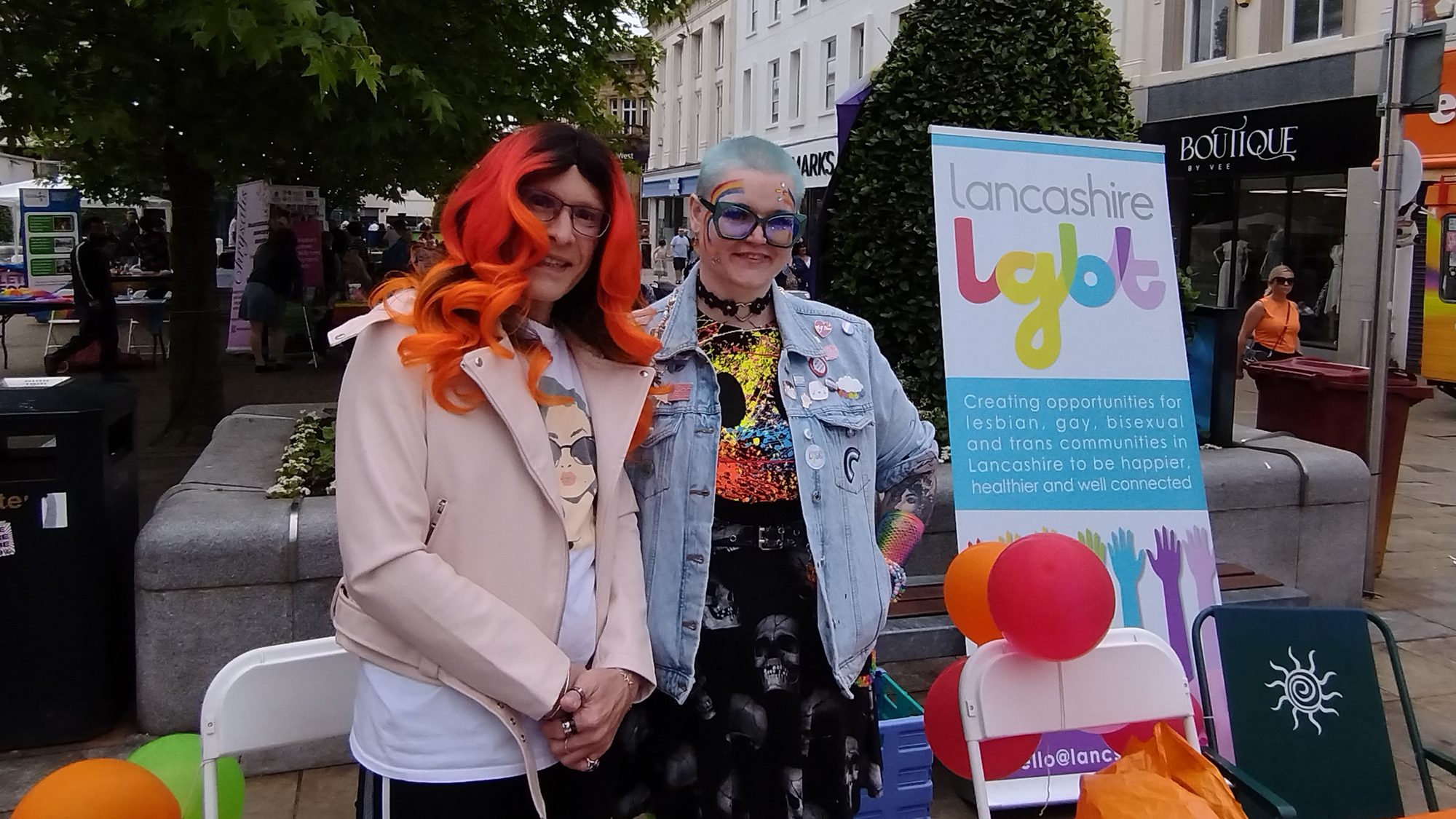 Two Lancashire LGBT volunteers beside the charity's banner at a town centre event